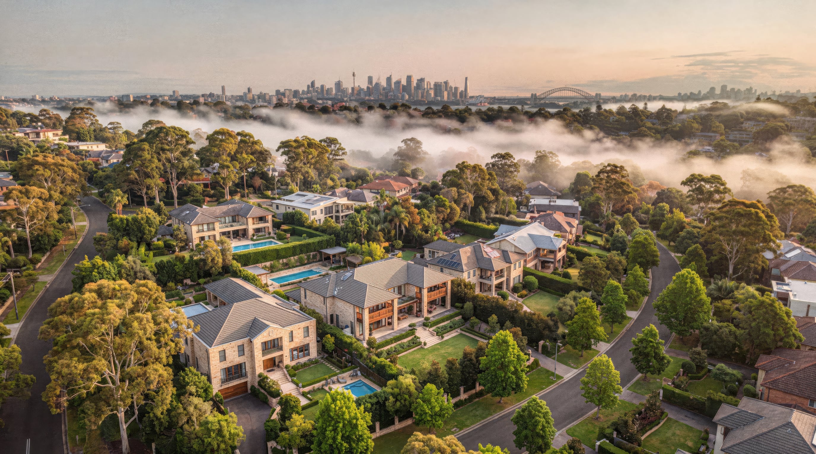 An aerial over an affluent leafy Hills neighbourhood at first light, large modern homes among green canopy and quiet streets, soft pink mist settling over the rooftops and the distant Sydney skyline on the horizon.