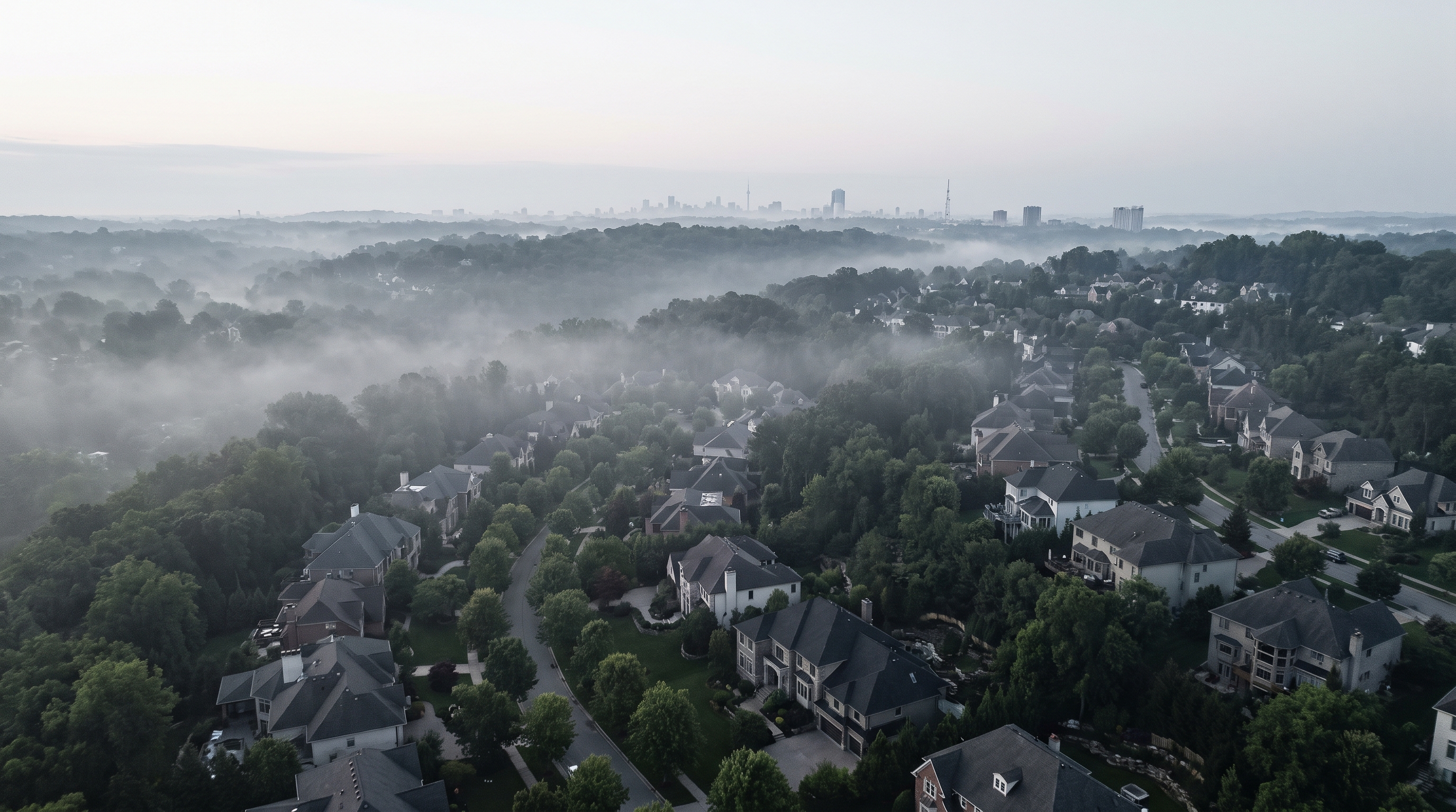 A high aerial over a quiet prosperous Hills neighbourhood on a still misty morning, large modern homes among mature trees fading into low silver-grey mist, the distant Sydney skyline pale on the horizon, an alternate framing.