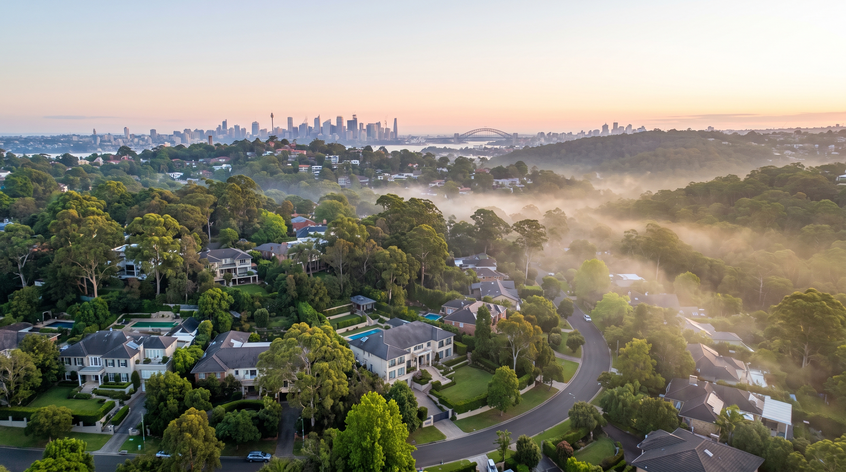 A high wide aerial over a leafy affluent Hills neighbourhood, large modern homes and gardens across rolling green canopy wrapped in gentle low mist, the distant Sydney skyline on the far horizon, an alternate framing.